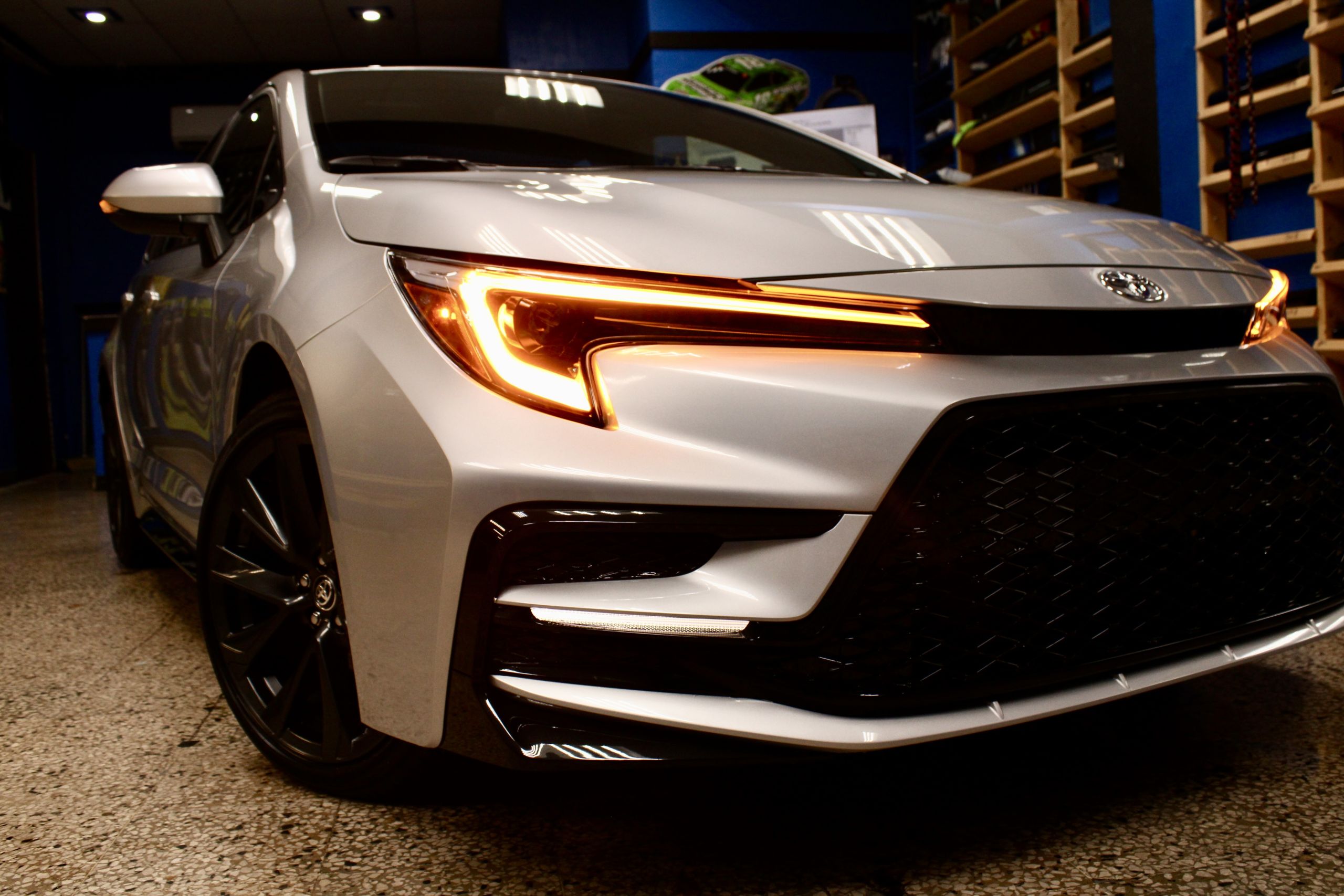 Toyota Corolla SE blanco con las luces delanteras encendidas